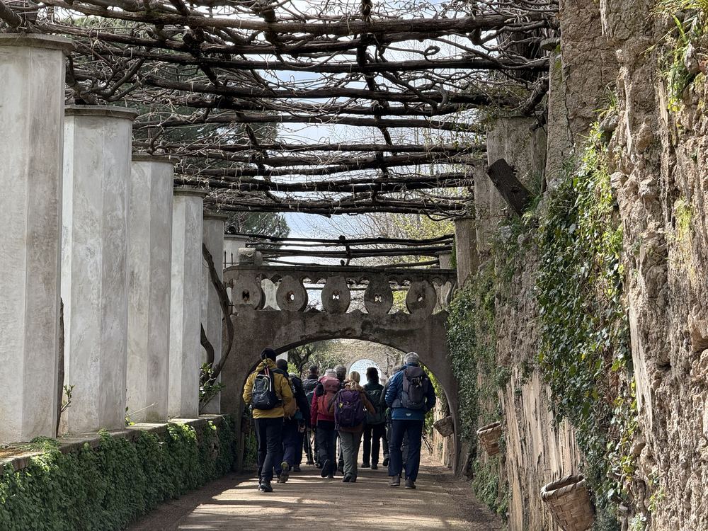 Hikers walking under a stone pergola between Ravello and Amalfi